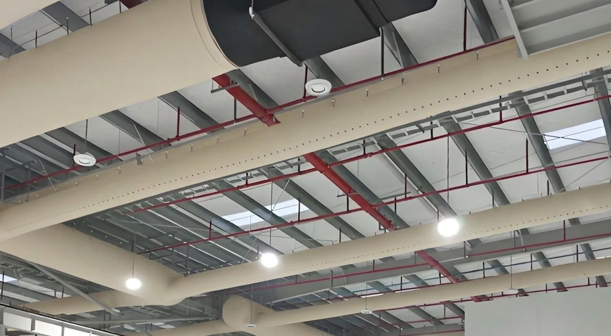 Fabric duct and sheet metal duct side by side in the same facility